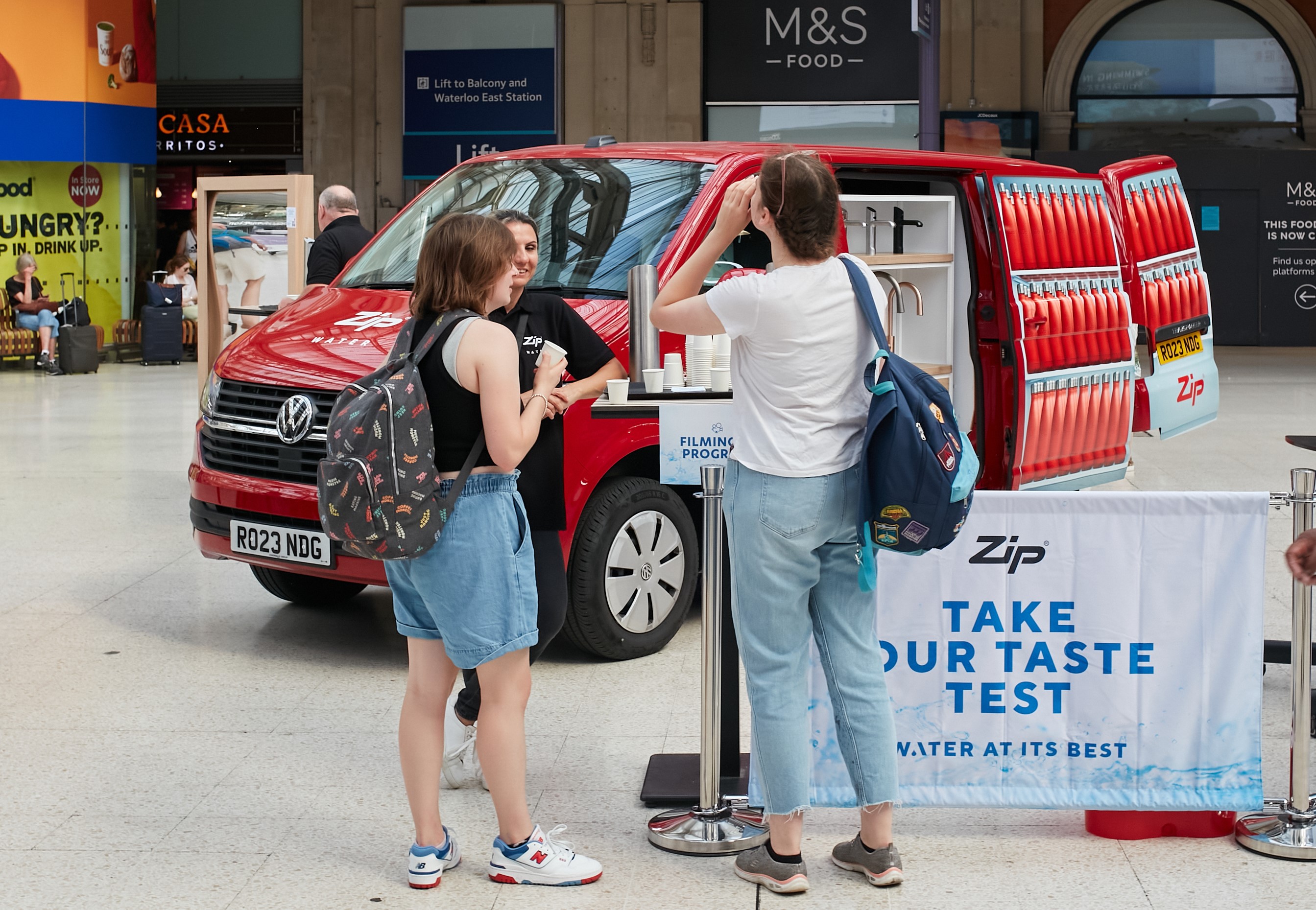 two people tasting water in front of a Zip Water branded van