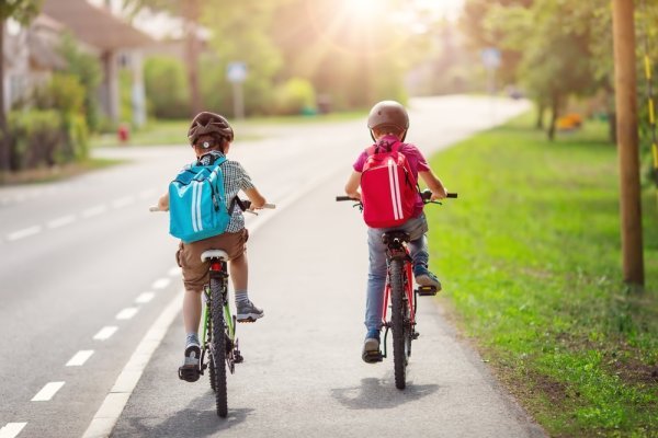 Two children with backpacks cycling to school.