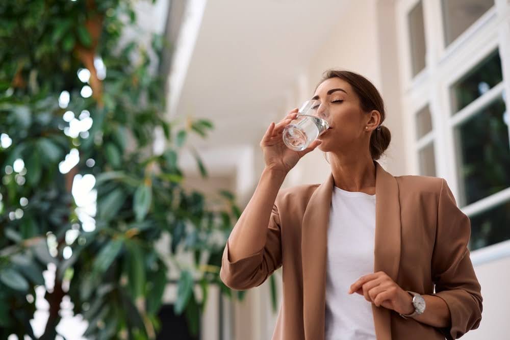 A woman drinking a glass of water outside