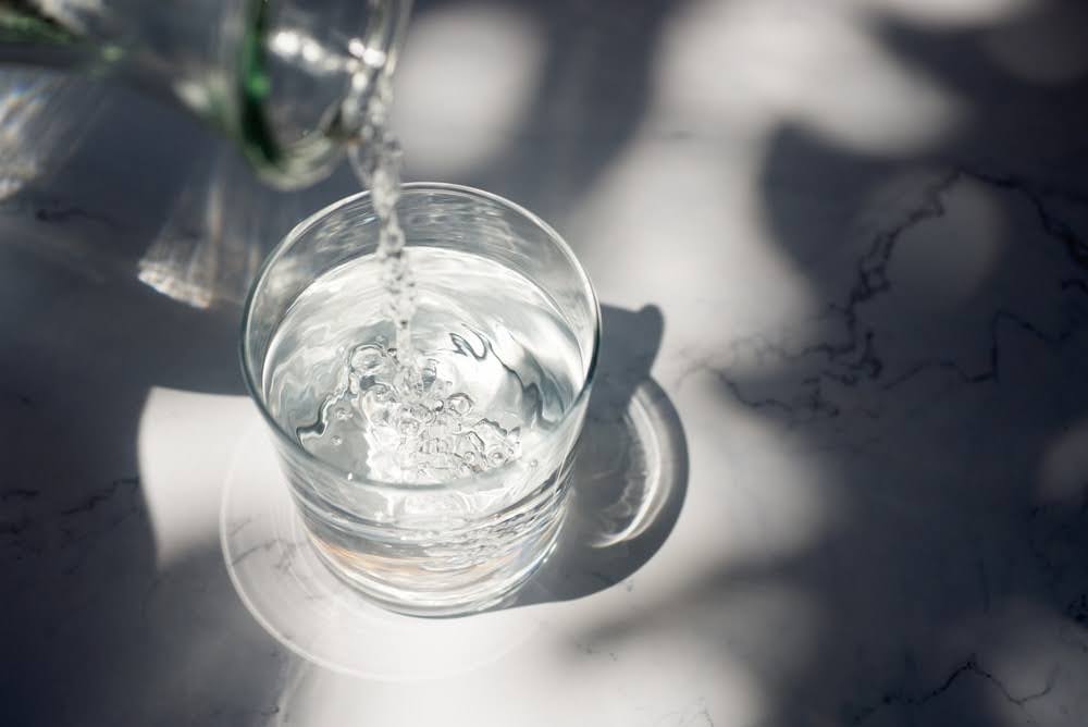 Water being poured into a glass on a marble counter