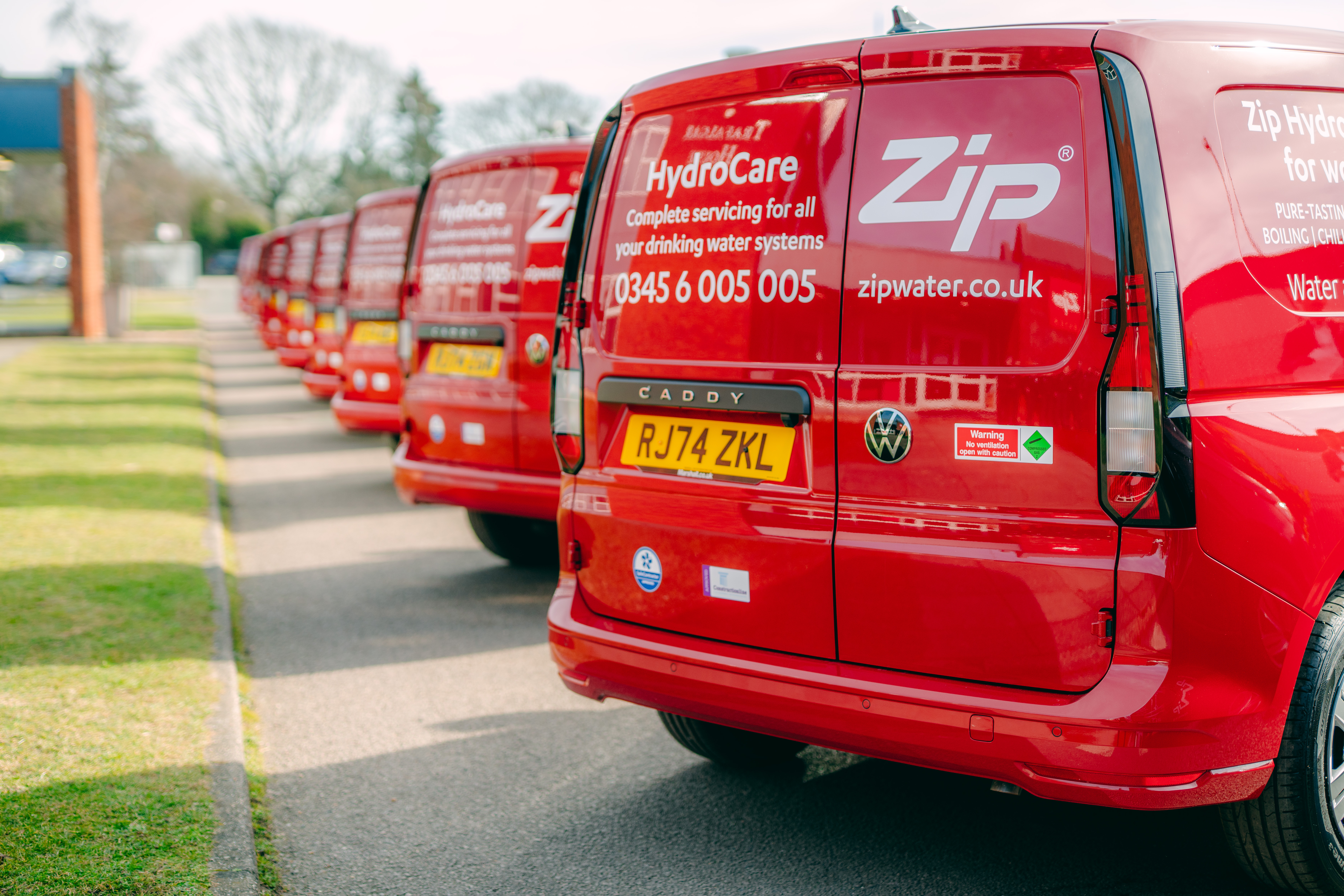 Six red Zip Water HydroCare vans in a row outside
