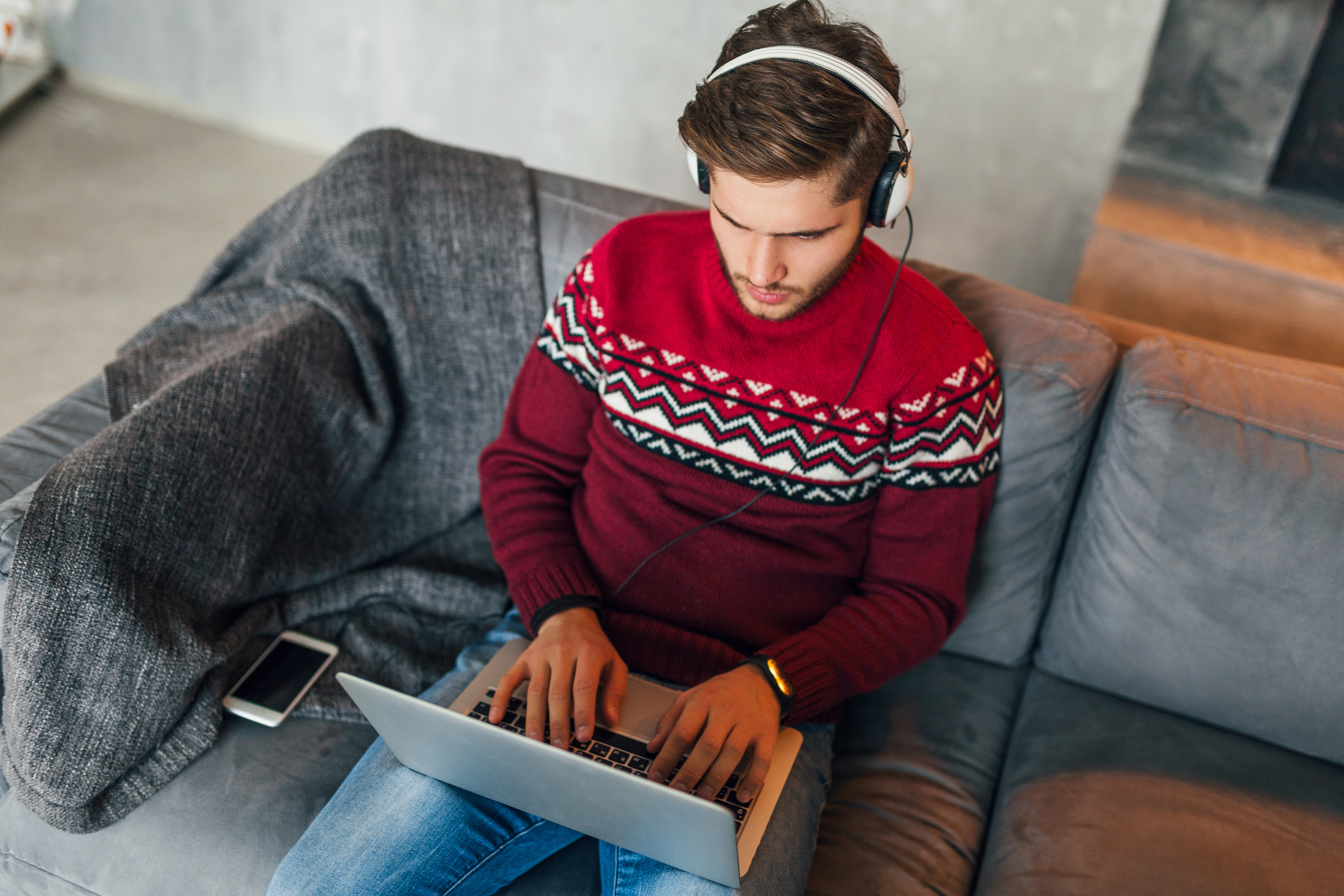 A remote worker working on a laptop sat on a sofa