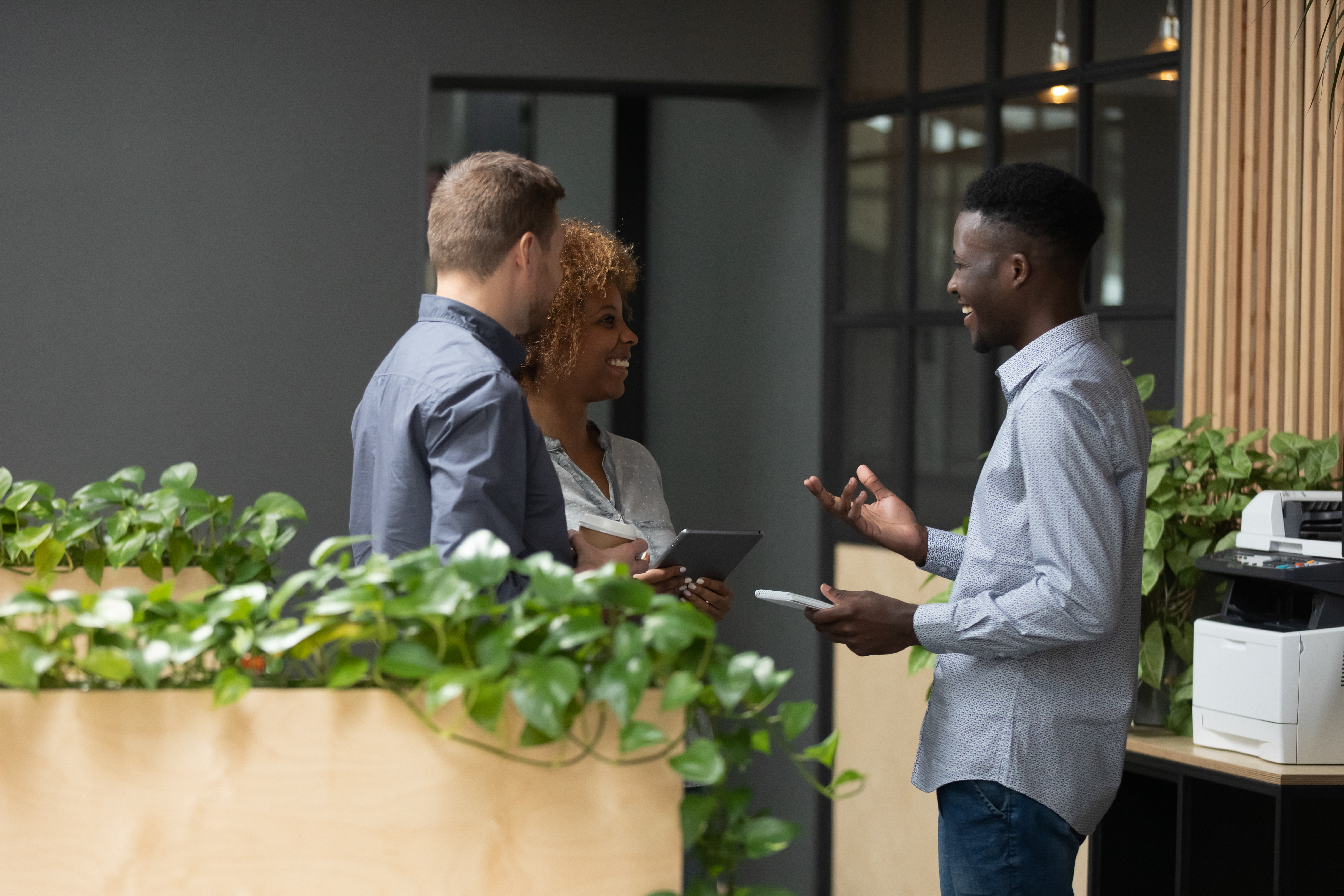 Office workers chatting surrounded by green plants