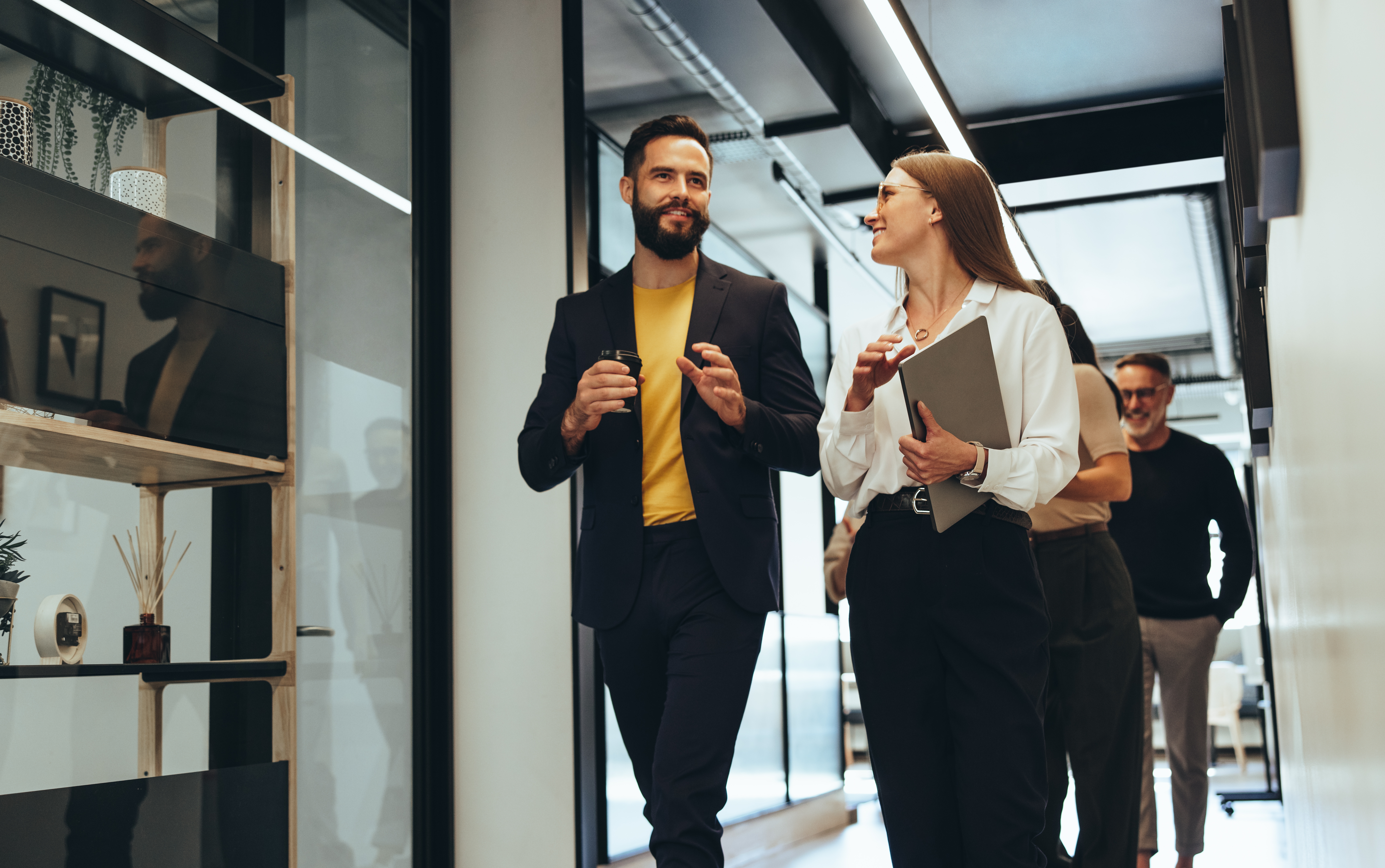 two colleagues chatting while walking through an office space 