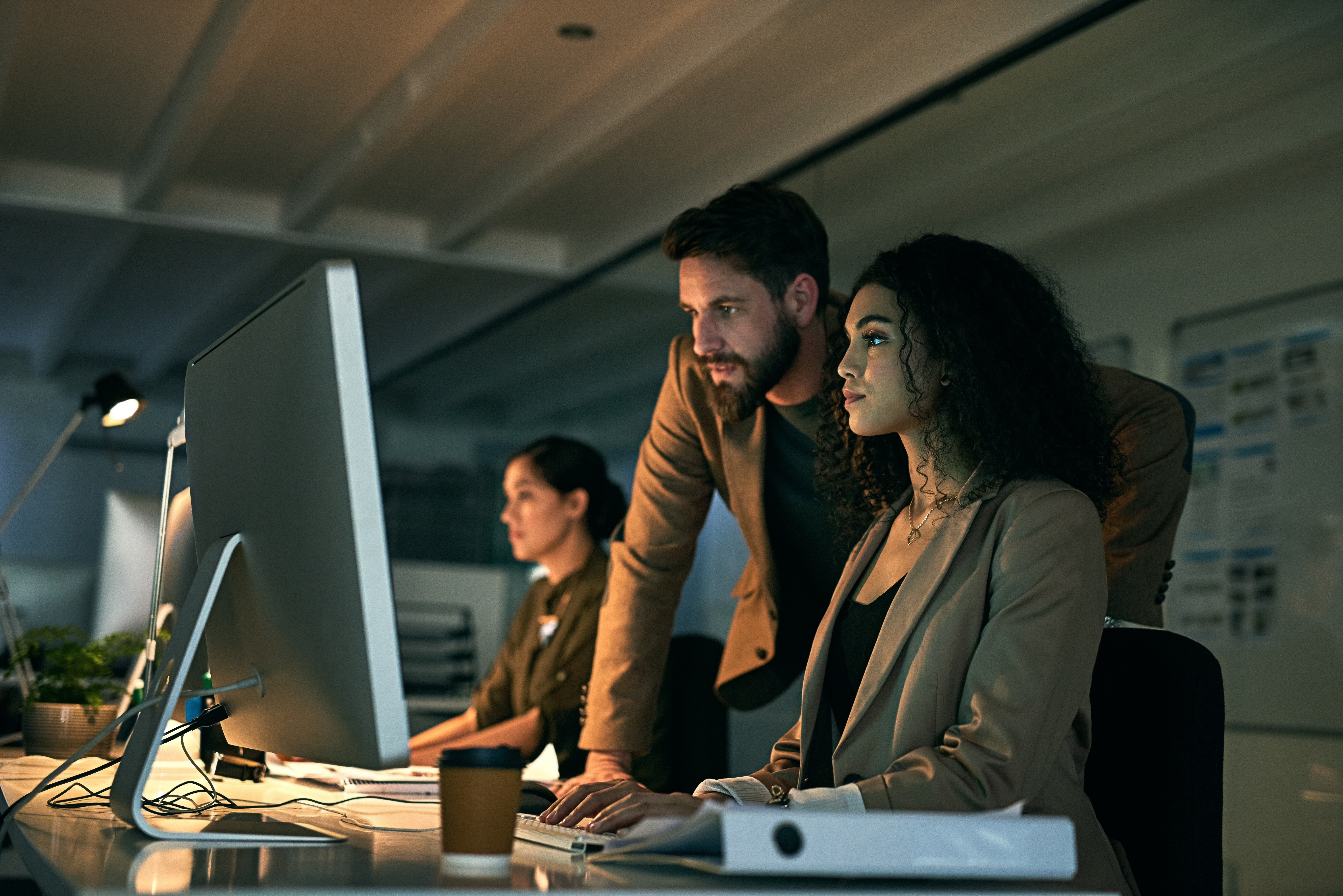 Colleagues conversing in front of a desktop computer